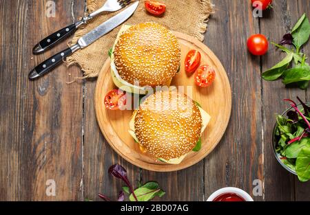 Frühstück zwei Burger mit Huhn, frittiertem Ei und Käse auf rustikalem Holzhintergrund. Draufsicht Stockfoto