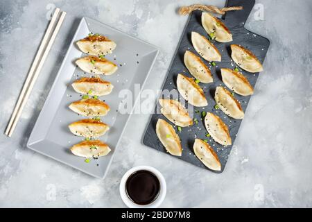 Japanischer Gyoza- oder Knödelsnack mit Sojasoße auf Betongrund. Draufsicht Stockfoto