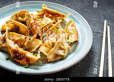 Japanischer Gyoza- oder Knödelsnack mit Sojasoße auf schwarzem Steingrund Stockfoto