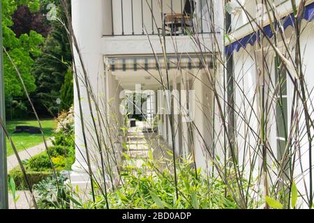 Großes Hotel zum Entspannen mit dekorativen grünen Pflanzen im Garten. Sommerlandschaft in Baden-Baden. Stühle und Tisch auf einem Balkon. Stockfoto