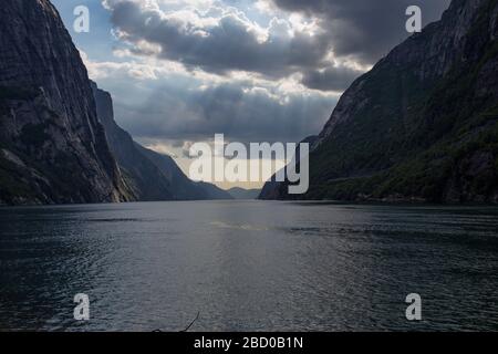 Abends ein schöner Fjord-Talblick, umgeben von Bergen, bewölktem blauem Himmel. Stockfoto