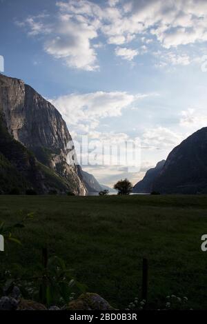 Abends ein schöner Fjord-Talblick, umgeben von Bergen, bewölktem blauem Himmel. Stockfoto