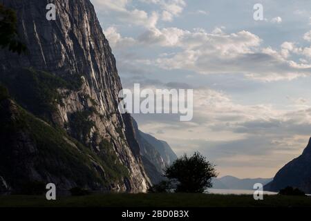 Abends ein schöner Fjord-Talblick, umgeben von Bergen, bewölktem blauem Himmel. Stockfoto