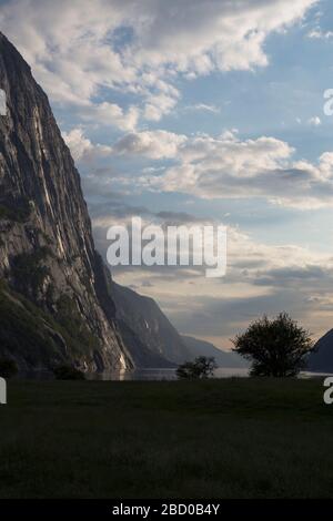 Abends ein schöner Fjord-Talblick, umgeben von Bergen, bewölktem blauem Himmel. Stockfoto