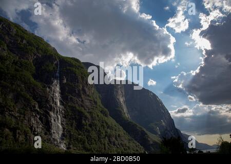 Abends ein schöner Fjord-Talblick, umgeben von Bergen, bewölktem blauem Himmel. Stockfoto