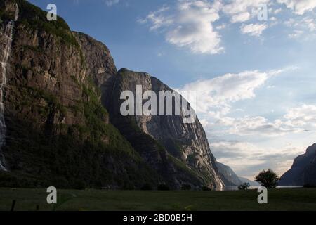 Abends ein schöner Fjord-Talblick, umgeben von Bergen, bewölktem blauem Himmel. Stockfoto