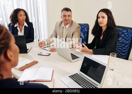 Seriöses Business Team, das am Treffpunkt sitzt und wichtige Themen und Entwicklungsstrategien diskutiert Stockfoto