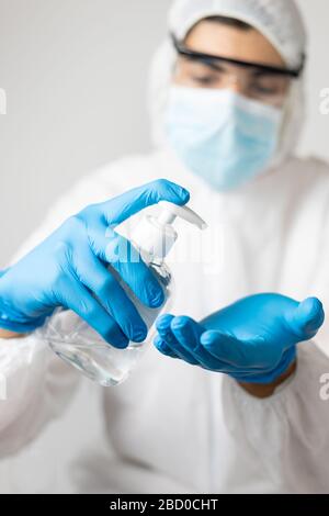 Forscher mit Latexhandschuhen und Schutzkleidung gegen Coronavirus Covid-19 durch Waschen der Hände mit Alkohol Stockfoto