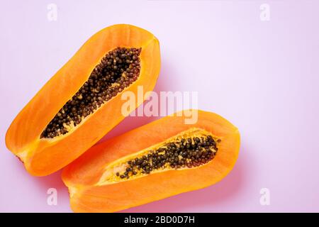 Nahaufnahme der Hälften reifer Papaya-Früchte mit Samen. Reife frische Papayafrucht isoliert auf pinkfarbenem Hintergrund. Draufsicht. Vertikaler Schuss. Exotische tropische Frui Stockfoto