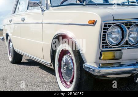 Retro-Auto mit Blendung auf Chrom-Details. Seiten-und Vorderansicht des Scheinwerfers. Vintage beige Auto Stockfoto