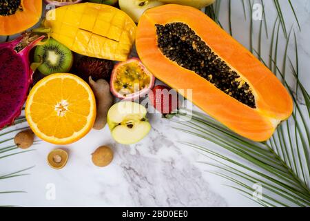 Gruppe exotischer tropischer Früchte. Papaya, Mango, Drachenfrucht, Passionsfrucht, Kiwi, Erdbeere, apfel, Banane, Orange, Langaan, grüne Blätter auf weißer BA Stockfoto