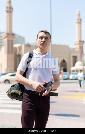 Vor dem Hintergrund einer islamischen Moschee steht ein 35-40 Jahre alter Touristenmann mit einer Karte in den Händen Stockfoto