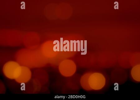 ฺBlurred roter und oranger Bokeh-Hintergrund. Verwischen Sie abstrakten Hintergrund von urbanem Licht. Warmes Licht mit wunderschönem Muster aus runder Bokeh. Rotes Licht im Stockfoto