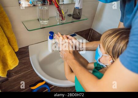 Vater lehrt seinen Sohn, seine Hände richtig zu waschen. Vater und Sohn in medizinischen Masken wegen Coronoviren. Epidemie. Bleiben Sie zu Hause. Waschen Sie Ihre Hände Stockfoto