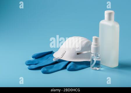 Anti-Virus-Schutzkit auf blauem Hintergrund, Maske, Gummihandschuhe, Händededesinfektionsflaschen, antiseptisches Gel. Stockfoto