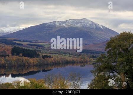 Blick über Loch Tummel und Bäume in Herbstfarbe auf den schneebedeckten Gipfel des Schiehallion-Berges in Perth und Kinross Schottland Stockfoto