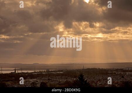 East Edinburgh, Schottland, Großbritannien. April 2020. Gottes Strahlen erleuchten den ansonsten trüben Himmel in Richtung East Lothian. Gottesstrahlen entstehen, wenn ein Raum eine dichte Mischung von Lichtstreumedien wie Gasmolekülen und Objekten enthält, die das Licht verschließen, so dass Schattenvolumina entstehen, die scheinbar Lichtstrahlen erzeugen, die von der Lichtquelle ausgehen. Temperatur ein mildes 10 Grad Celsius. Credit: Arch White/Alamy Live News. Stockfoto