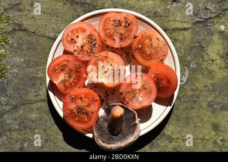 Runde Salattomaten mit getrockneten grünen Kräutern, die bereit sind, roh gegrillt oder gekocht zu werden, haben süß sauren Geschmack und saftiges Fleisch klassifiziertes Obst Stockfoto