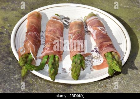 Niedrig karbiger Knoblauchbutter Prosciutto Schinken gewickelter Spargel, der auf den Holzkohlegrill geworfen wird Party Fingerfood einfach und schnell zu Hause zu machen Stockfoto