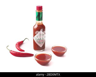 Tabasco Sauce mit gläsernen Schalen voller Soße auf weißem Hintergrund isolierte Zusammensetzung Stockfoto