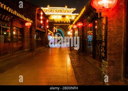 Die Dongguan-Straße, die auf Dongmen, das Osttor, blickt, leuchtete nachts mit roten Laternen in Yangzhou, Provinz Jiangsu, China. Stockfoto