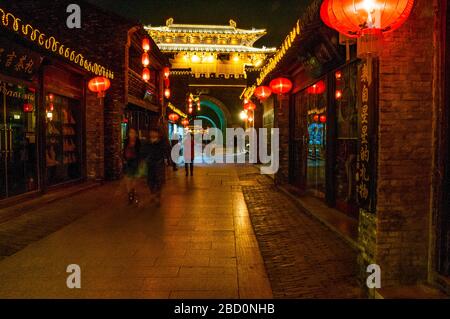 Die Dongguan-Straße, die auf Dongmen, das Osttor, blickt, leuchtete nachts mit roten Laternen in Yangzhou, Provinz Jiangsu, China. Stockfoto