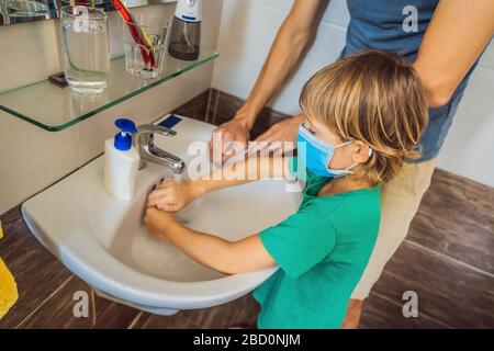 Vater lehrt seinen Sohn, seine Hände richtig zu waschen. Vater und Sohn in medizinischen Masken wegen Coronoviren. Epidemie. Bleiben Sie zu Hause. Waschen Sie Ihre Hände Stockfoto