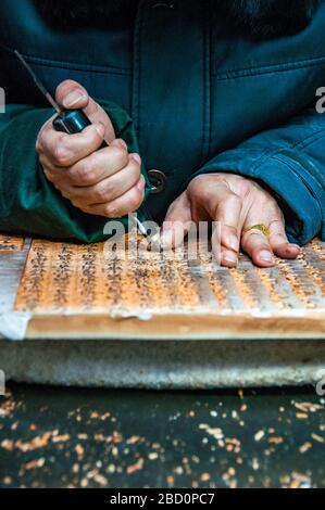 Ein Alter Mann zeigt die traditionelle Schnitzerei-Methode zum Block Drucken bei Yangzhou Museum produzieren Stockfoto