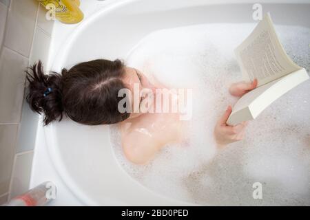 Junge Frauen, die sich im Bad entspannen und ihr Buch lesen Stockfoto
