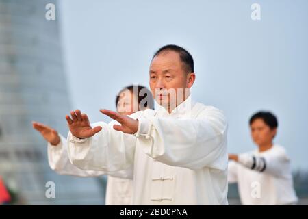 Huzhou, China, Oktober 2019; Nahaufnahme eines Mannes Teil einer großen Gruppe von Menschen, die am frühen Abend am Ufer des Tai-Sees Tai Chi und Yang praktizieren Stockfoto