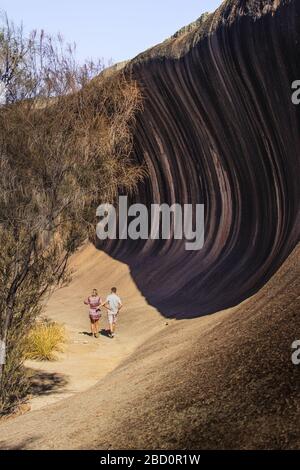 Ein Paar, das in einer unsual Felsformation namens Wave Rock im Westen Australiens wandert Stockfoto