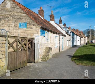 Eine Reihe alter Reihenhäuser in Castlegate, Pickering, North Yorkshire mit Sonnenschein und blauem Himmel Stockfoto