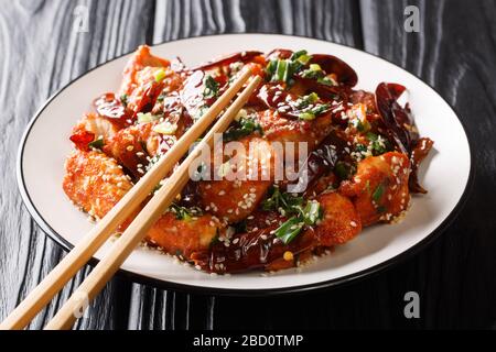 Würzig gebratenes Mala-Huhn mit Sesamsamen und Grüns in einer Platte auf dem Tisch anrühren. Horizontal Stockfoto