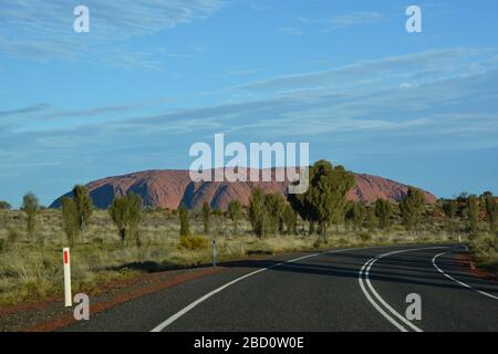 Uluru, Australien-Juli 2019; Panoramablick von der Kurve in der Straße auf große Sandsteinfelsen im südlichen Teil des Northern Terr Stockfoto