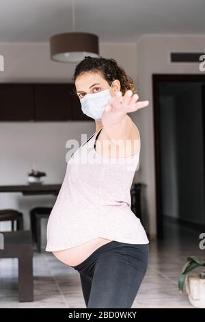 Schwangere Mädchen, die zu Hause trainieren, während der Kovid-19-Coronavirus-Quarantäne Stockfoto