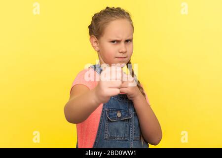 Porträt des mutigen kämpfenden kleinen Mädchens in Overalls, das mit Boxgeste steht, erfroren und Fäuste zum Durchschlagen hält, wütendes Kind vor Offen verteidigt Stockfoto