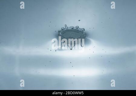 Wassertropfen spritzen in einem Glas grau gefärbt Stockfoto