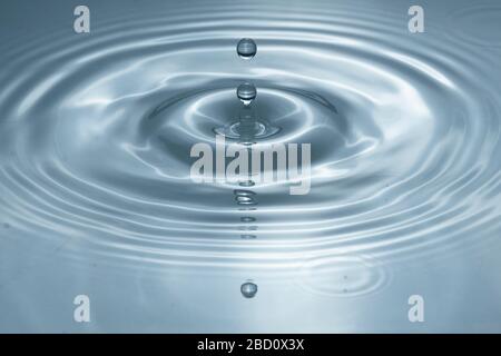Wassertropfen spritzen in einem Glas grau gefärbt Stockfoto