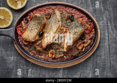 Mit Tomatensauce gedämpfter Perch, provenzalisches Essen in Pfanne servieren. Draufsicht, Kopierraum. Stockfoto