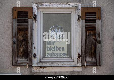 06. April 2020, Hessen, Frankfurt am Main: "Wir bleiben zu Hause" steht auf einem Schild, das hinter einem Fenster unter dem Logo des Fußball-Bundesligisten Eintracht Frankfurt steckt. Virologen haben an die Bevölkerung appelliert, über die Osterferien zu Hause zu bleiben. Foto: Boris Roessler / dpa Stockfoto