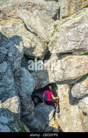 Junge Trekkkerin besucht spektakuläre granitische Felskanel und Schlaglöcher, die von Flutströmen erodiert werden. Cornalvo Naturpark, Extremadura, Spanien Stockfoto