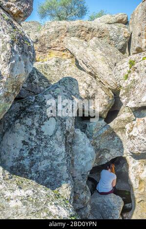 Junge Trekkkerin besucht spektakuläre granitische Felskanel und Schlaglöcher, die von Flutströmen erodiert werden. Cornalvo Naturpark, Extremadura, Spanien Stockfoto