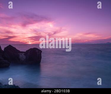 Lange Belichtung photograhy am felsigen Kato Petres Strand Landschaft in der Abenddämmerung. Rhodos, Griechenland Stockfoto