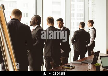 Silhouetten von Menschen gegen das Fenster. Ein Team junger Geschäftsleute, die in einem Büro zusammenarbeiten und miteinander kommunizieren. Unternehmens-Business und Stockfoto