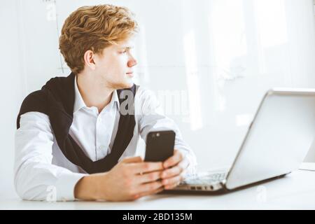 Junger Geschäftsmann, der im Büro am Laptop arbeitet Stockfoto