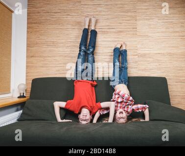 Geschwister, die auf dem Kopf stehen und verrückt werden, steckten zu Hause in Selbstisolation fest. Quarantäne- und Sperrmaßnahmen gegen die Ausbreitung von Coronavir Stockfoto