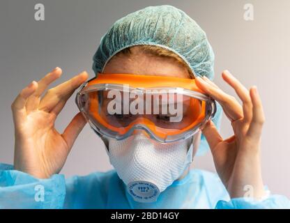 Dresden, Deutschland. April 2020. ABBILDUNG - EIN Zahnmediziner legt eine Schutzbrille an und trägt ein Atemschutzgerät FFP3, bevor er einen Corona-Patienten in einem Zahnbüro behandelt. (Posierte Szene) Credit: Robert Michael / dpa-Zentralbild / dpa / Alamy Live News Stockfoto