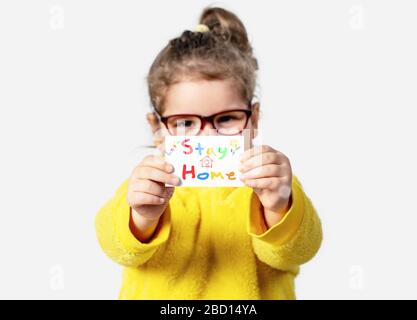 Adorable Baby girl hält ein Papier mit einem Aufenthalt zu Hause Notiz für die Isolation. Corona-Virus-Outbreaking- und Quarantänekonzept Stockfoto