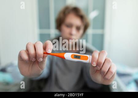 Krankes Mädchen mit einem Thermometer, das in Gewebe niest. Grippe. Eine Frau erwischte eine Erkältung Stockfoto