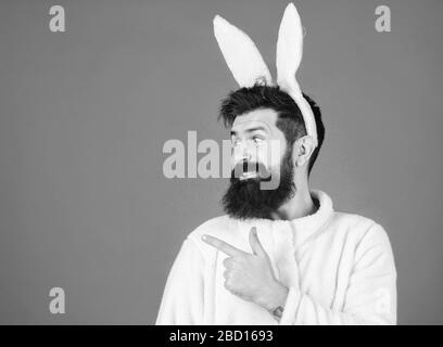 Mann trägt einen kuscheligen Plüschanzug. Lustiger Hünenmann mit Bart und Schnurrbart. Konzept des Ostersymbols. Kerl bärtiger Flusspferd süßer sanfter, bunter langer Ohren blauer Hintergrund. Respekt vor Traditionen. Osterhase. Stockfoto